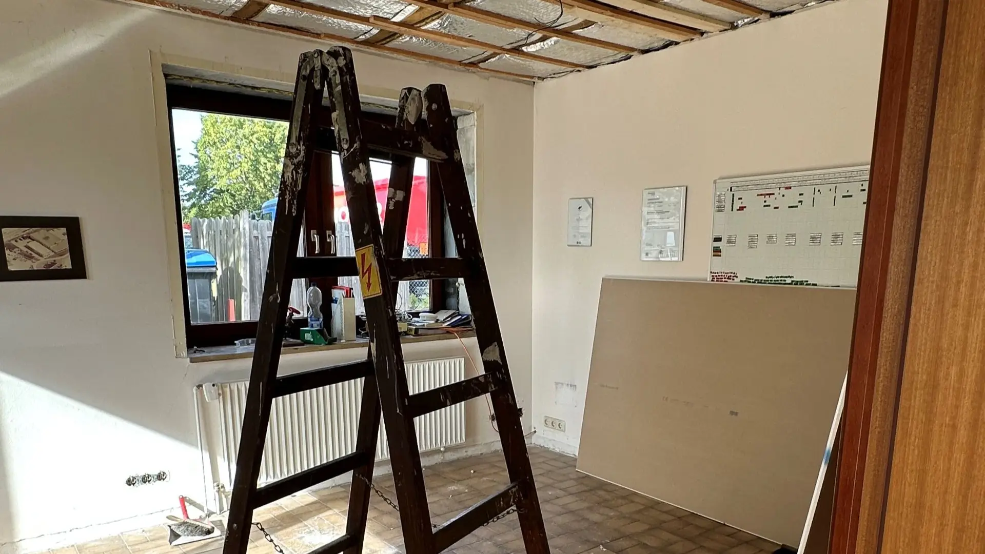 Raum der renoviert wird in dem eine Holzleiter steht und die Deckenverkleidung fehlt