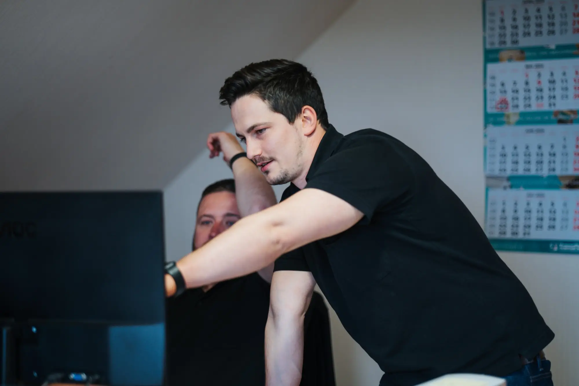 Mitarbeiter zeigt einem anderen Mitarbeiter am Monitor etwas