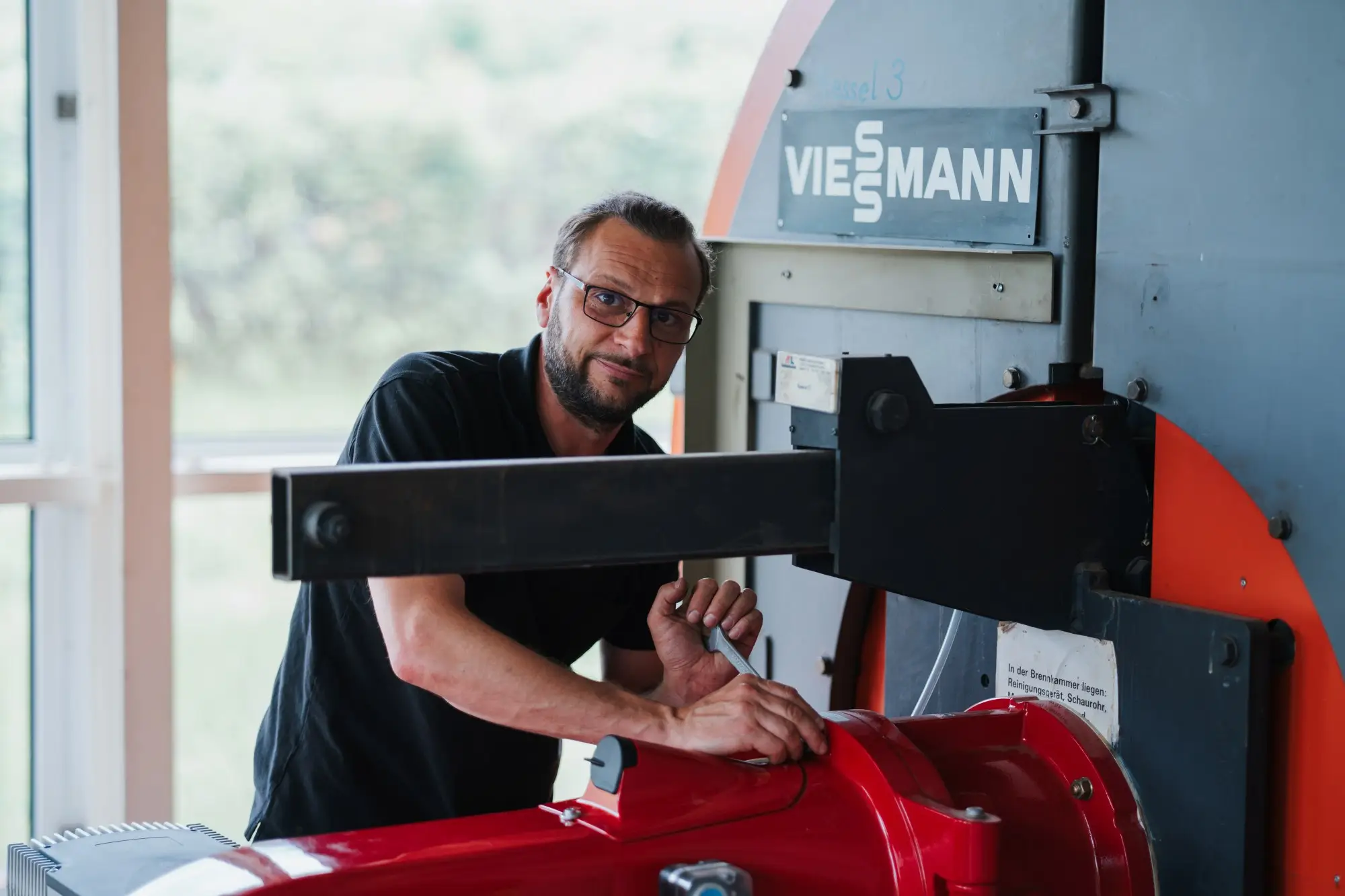 Mitarbeiter mit einem Schraubenschlüssel an einem Heizkessel