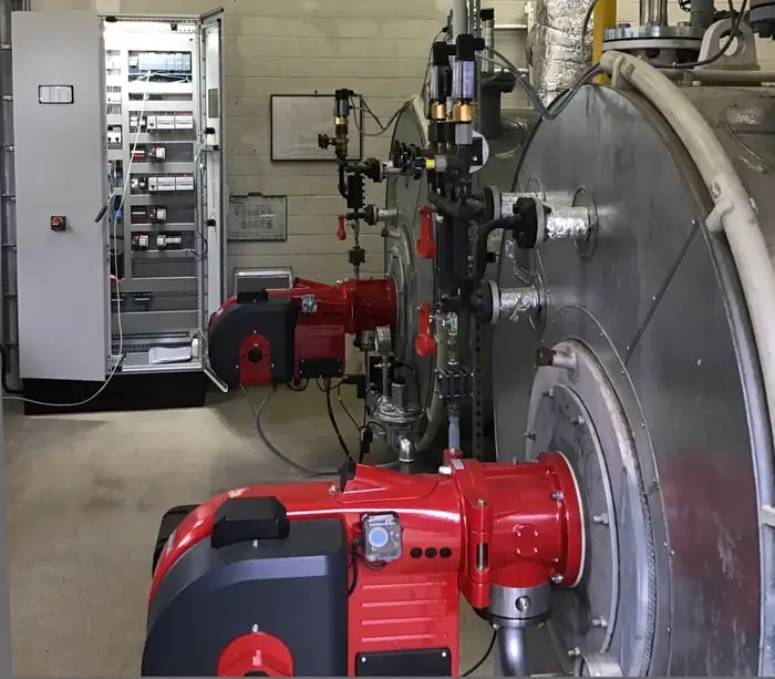 Heizkessel mit Schaltschrank im Hintergrund